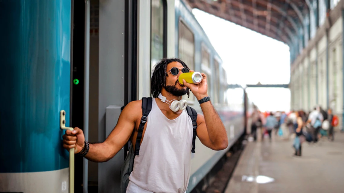Guy stepping out of a train while sipping a microdosing drink from a can
