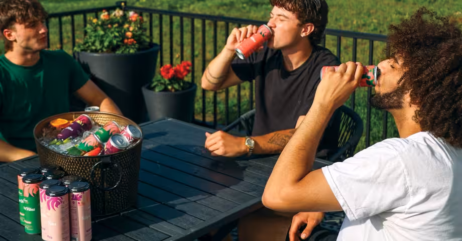 3 guys sitting around a table on a patio drinking Wunder THC beverages