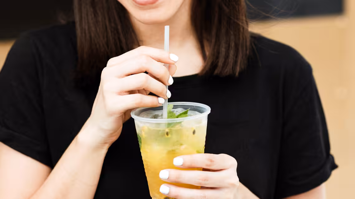 close-up photo of a glass of beverage that a woman wearing a black t-shirt is holding